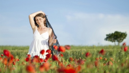 Young casual woman relaxing in poppy fieldの写真素材