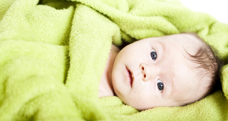 Happy baby covered in green towel の写真素材