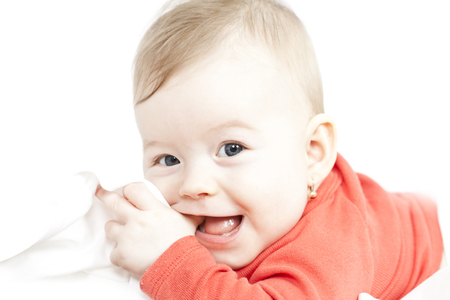 Sweet baby girl lying on the bed sucking on its fingerの写真素材