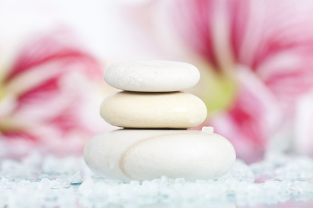 Spa stones and pink lilly flower on white backgroundの写真素材