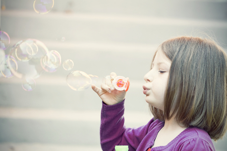 Retro styled photo of young girl blowing soap bubblesの写真素材