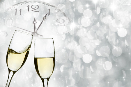 Glasses with champagne against holiday lights and clock close to midnightの写真素材