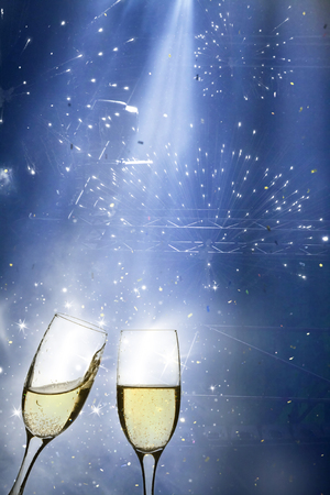 Glasses with champagne against fireworks and holiday lightsの写真素材