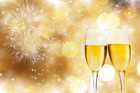 Glasses with champagne against fireworks and holiday lightsの写真素材