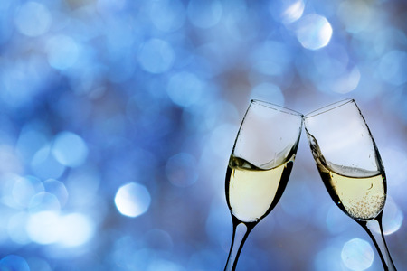Glasses with champagne against fireworks and holiday lightsの写真素材