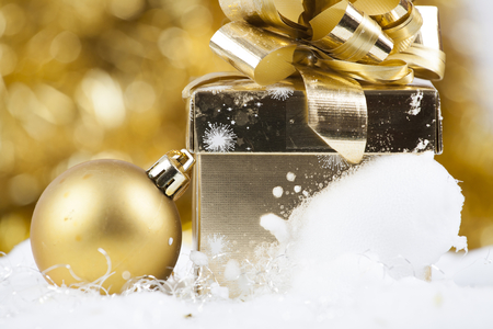 Golden Christmas background with snow, golden Christmas ball and gift boxの写真素材