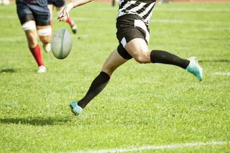 Rugby player kicking hard the oval ballの写真素材