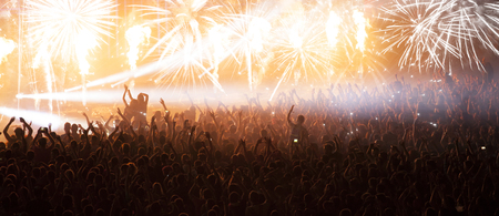 Cheering crowd at concert in front of stage with pyrotechnicsの写真素材