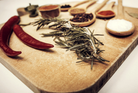 Various colorful spices on kitchen spoons over grunge wooden tableの写真素材