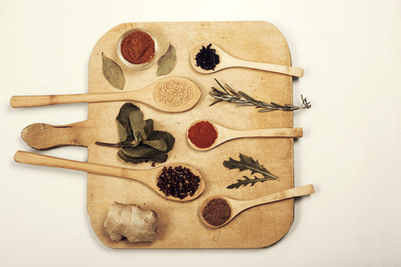 Various colorful spices on kitchen spoons over grunge wooden tableの写真素材