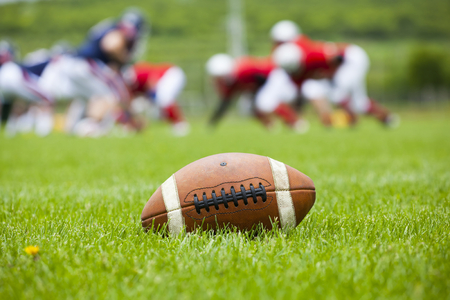 American football ball resting on the grass of the fieldの写真素材