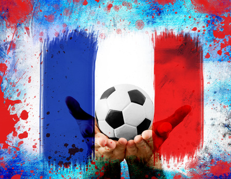 Soccer ball in the hands of a man on red,blue, and white backgroundの写真素材