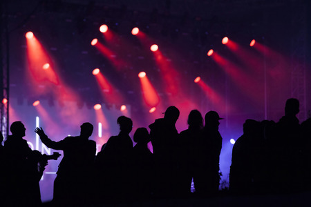Cheering crowd in front of bright colorful stage lightsの写真素材
