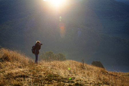 Woman photographer in the mountains on an early autumn mornining