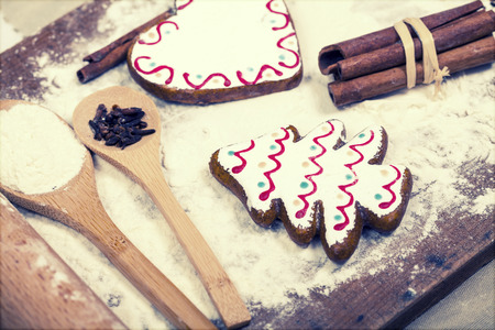 Vintage Christmas background with gingerbread cookies, spices and flour over wooden background