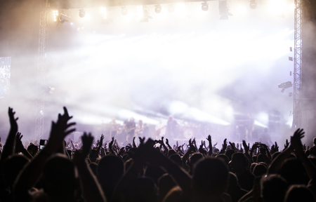 Photo of many people enjoying rock concert, crowd with raised up hands dancing in nightclub, audience applauding to musician band, night entertainment, music festival, happy youth, luxury partyの写真素材