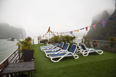 Boat upper deck with blue beach chairs, empty, no people, overlooking Halong bay, Vietnamの写真素材