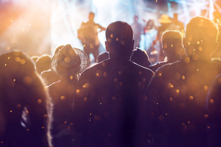 Photo of many people enjoying rock concert, audience applauding to musician band, night...