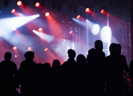Crowd cheering at a concert in front of the reflector lightsの写真素材