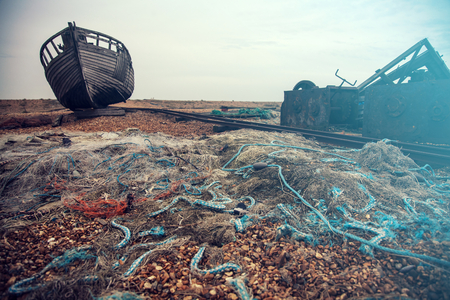 Blue fishing nets and lengths of rope and old boat at Dungeness pebble beach, Kent, Englandの写真素材