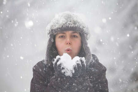 Happy woman blowing snow in winter forest.の写真素材