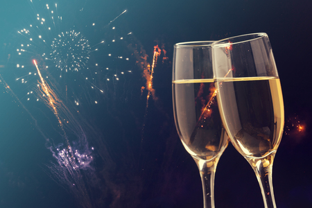 Glasses with champagne against fireworks and holiday lights - Celebrating the New Yearの写真素材