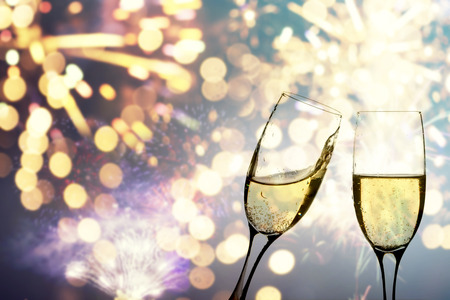 Glasses with champagne against fireworks and holiday lights - Celebrating the New Yearの写真素材