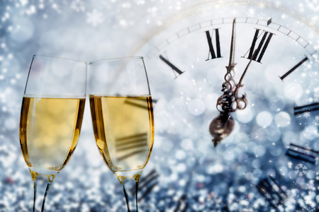 Glasses with champagne against fireworks and clock close to midnight - Celebrating the New Yearの写真素材
