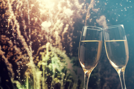 Glasses with champagne against fireworks and holiday lights - Celebrating the New Yearの写真素材