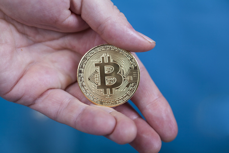 Golden Bitcoin Cryptocurrency in man`s hand. New Virtual money concept.