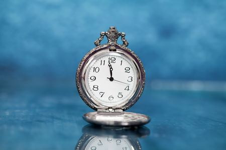 Vintage clock closed to midnight on blue wooden background