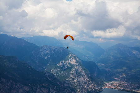Paraglider flying over mountains and lake in summer dayの写真素材