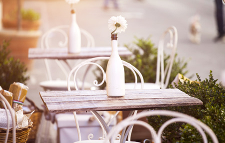Cozy terrace on an italian street with white chairs and white flowersの写真素材