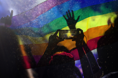 Pride community at a parade with hands raised and the LGBT flag - symbol of love and toleranceの写真素材