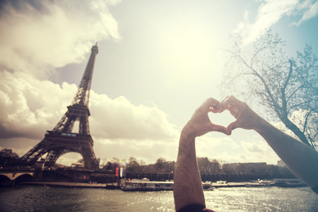 Love in Paris - hands forming a heart shape in front of the Eiffel Towerの写真素材