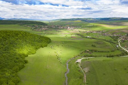 Aerial view of endless lush pastures and farmlands of Transylvania. Beautiful romanian countryside with emerald green fields and meadows. Rural landscape on sunset.の写真素材