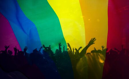 Pride community at a parade with hands raised and the LGBT flag - symbol of love and toleranceの写真素材