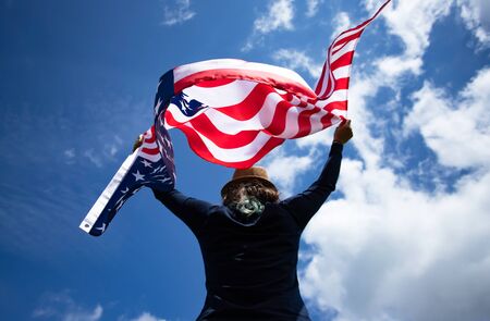 Young woman holding american USA flag. Independence Day or traveling in America concept.の写真素材