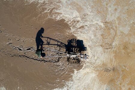 Aerial, drone view of man plowing paddy field ready for new rice crop in Thailand.の写真素材
