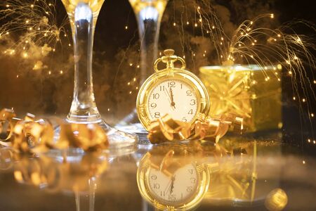 Champagne, clock close to midnight and Christmas decoration on sparkling holiday backgroundの写真素材