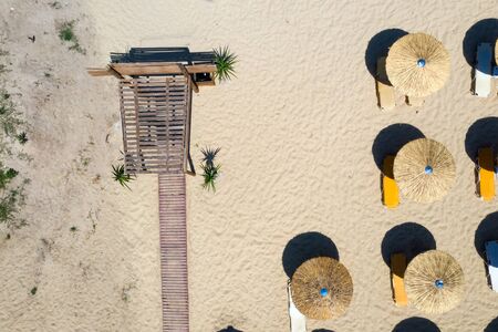 Aerial photograph of row of brown umbrellas on the beach in Greece.