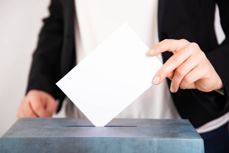 Hand of a voter putting vote in the ballot box. Election concept.