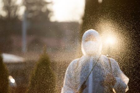 Man in protective equipment decontaminating and spraying on a public place as a prevention against Coronavirus disease 2019, COVID-19. Coronavirus pandemic.の写真素材