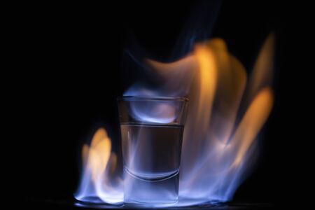 Glasses with burning alcohol on black background.