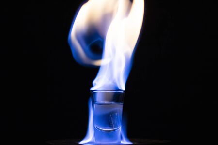 Glasses with burning alcohol on black background.