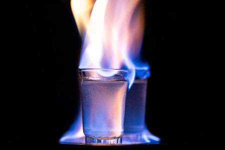 Glasses with burning alcohol on black background.