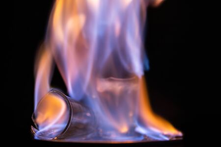 Glasses with burning alcohol on black background.