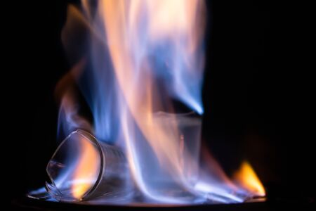 Glasses with burning alcohol on black background.