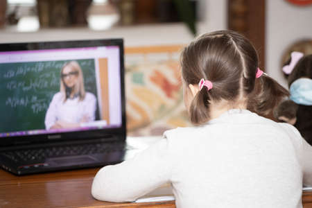Distance learning-online education. School girl watching online education classes and doing school...