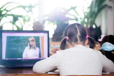 Distance learning-online education. School girl watching online education classes and doing school homework. COVID-19 pandemic forces children online learning.の写真素材